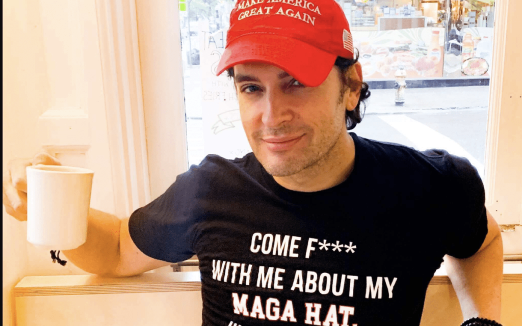 brandon straka wearing a maga hat and holding a cup of coffee