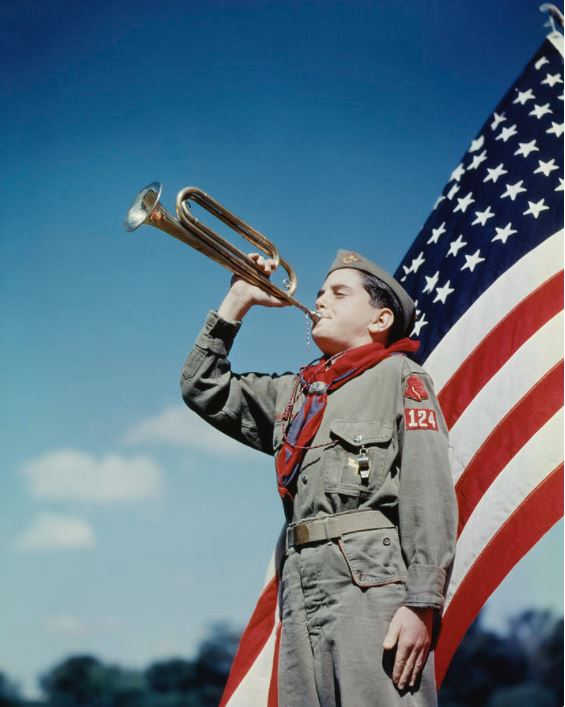 1950s era boy scout with bugle in front of american flag